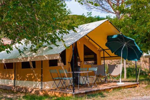 a tent with a table and chairs and an umbrella at Camping Onlycamp les Thézières in Taninges