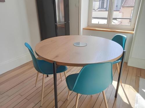 a wooden table and blue chairs in a room at Nancy Gare Centre Parking in Nancy