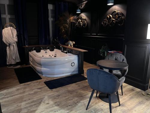 a bathroom with a tub and a table and a chair at La 104 Picasso Suite tendance dans maison réservée aux hôtes in Saint-Omer