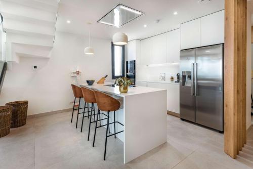 a kitchen with a counter with stools and a refrigerator at Casa Sol Luxury Rooftop Penthouse Gym Spa Pools in Marbella