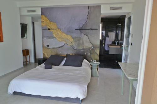 - une chambre avec un lit blanc et un mur dans l'établissement Coryphène pied dans l eau, aux Issambres