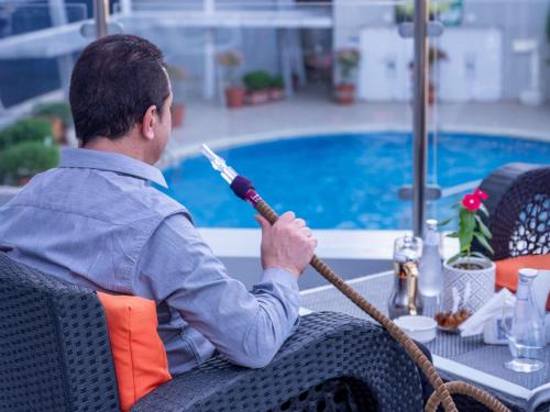 a man sitting at a table with a mop at Novotel Jazan in Jazan