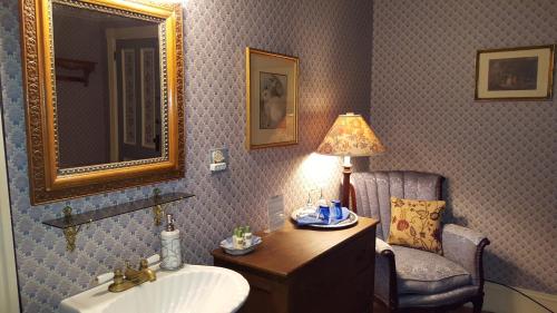 a bathroom with a sink and a mirror and a chair at Holidae House Bed & Breakfast in Bethel