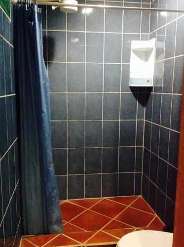 a black tiled bathroom with a toilet and a soap dispenser at Casa Manglar Villa in Puerto Jiménez