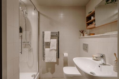 a white bathroom with a shower and a sink at Mason & Fifth, Westbourne Park in London