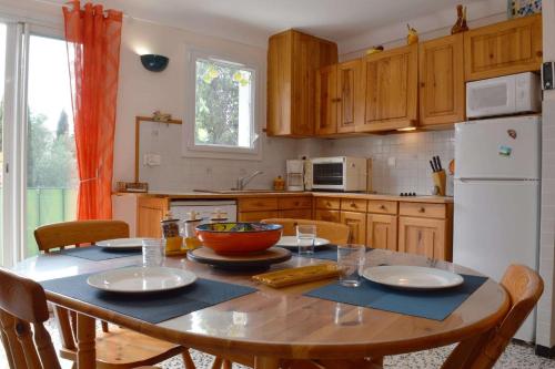 Il comprend une cuisine équipée d'une table avec des chaises et d'un réfrigérateur blanc. dans l'établissement Appartement 2 pièces - 4 personnes - ARGELES SUR MER AR860-B25, à Argelès-sur-Mer