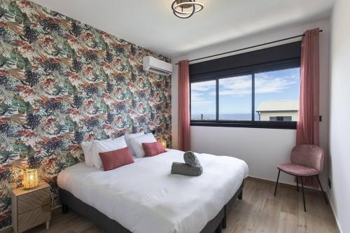 a bedroom with a large bed with a floral wall at VILLA BELLEVUE classée 5 Etoiles - 4 chambres - piscine chauffée proche de l'aéroport et du centre de St Denis in Sainte-Marie