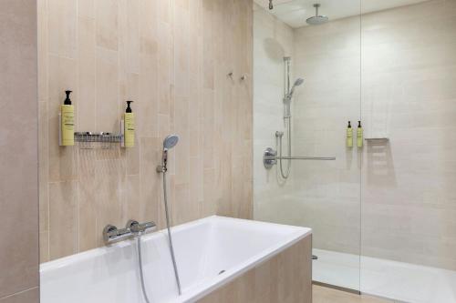 a bathroom with a tub and a shower with a glass door at Element Amsterdam in Amsterdam