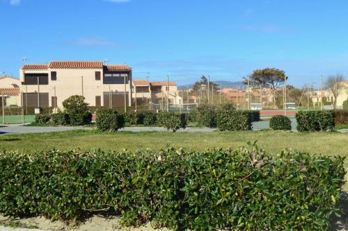 une haie dans un parc avec une maison en arrière-plan dans l'établissement Appart Studio 2 couchages PORT LEUCATE NATURISME PL010-423, à Leucate-Plage
