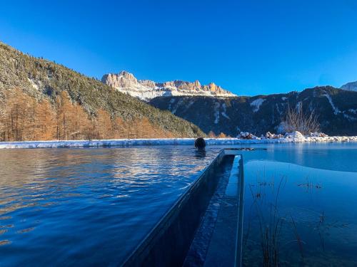 a boat on a lake with mountains in the background at Ansitz Velseck-Residence Hotel in Tires