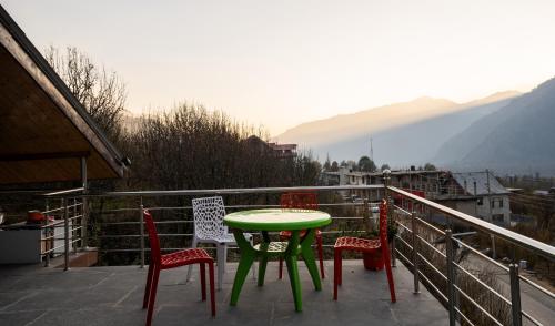 a table and chairs on a balcony with a view at Mellow- A Himalayan Home in Haripūr