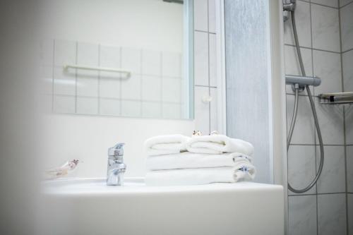 a bathroom with a sink and a shower with towels at Park Hotel Sellin in Ostseebad Sellin