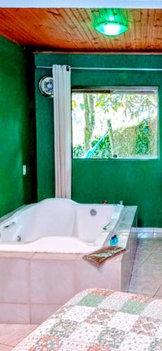a bathroom with a bath tub and a window at Pousada Maria Bonita in Macacos