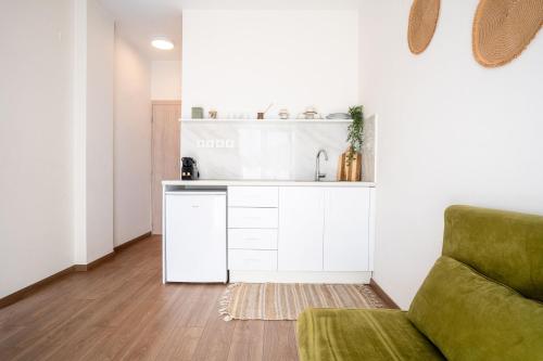 a living room with a green couch and a kitchen at Senaon Urban Living City Center in Heraklio Town