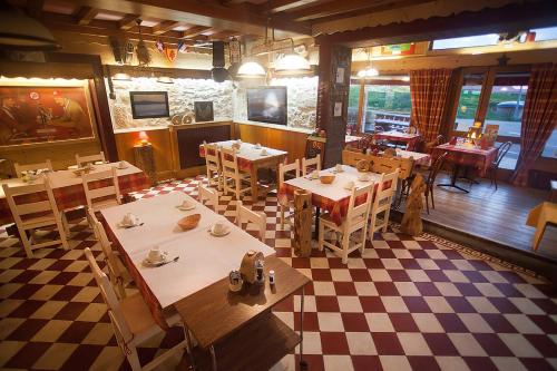 a restaurant with tables and chairs and a checkered floor at Logis hôtel Arbez Franco Suisse in Les Rousses