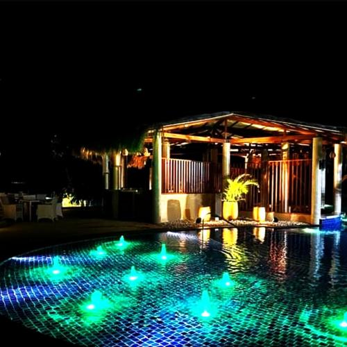 a swimming pool at night with blue and green lights at Mactan Newtown 8 Boulevard Deluxe Ocean View in Lapu Lapu City