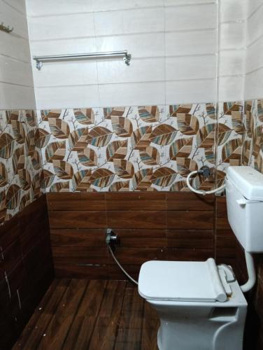 a bathroom with a toilet and a mosaic wall at Luxe Shree Krishna Kunj Villa in Ujjain