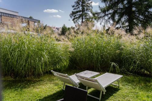 two chairs and a table in a yard with tall grass at Hotel Shuum Boutique - Destigo Hotels in Kołobrzeg