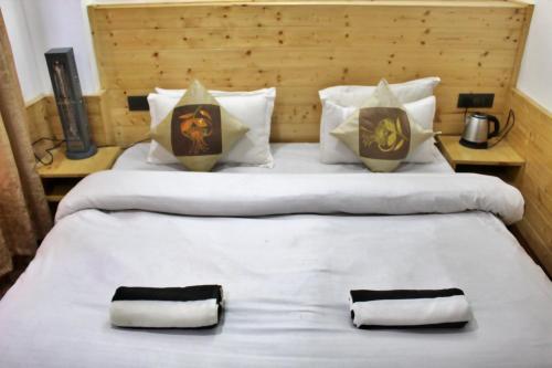 a large bed with two pillows and two towels at Apple Field House in Manāli