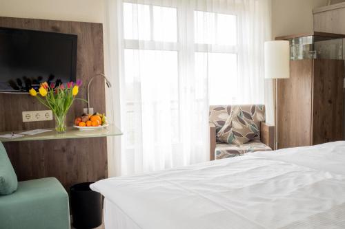 a bedroom with a bed and a window with a vase of flowers at Park Hotel Sellin in Ostseebad Sellin