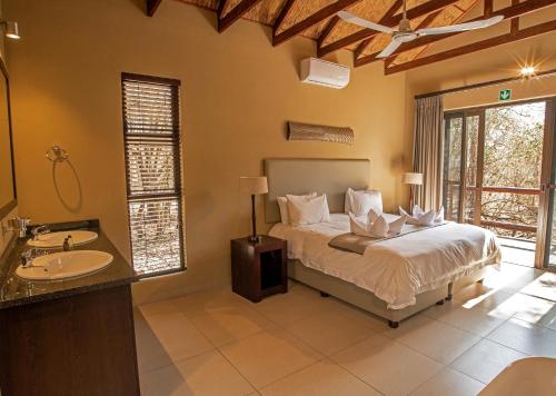 Un dormitorio con una cama y un lavabo en una habitación. en Mjejane Bush Camp by Dream Resorts, en Hectorspruit