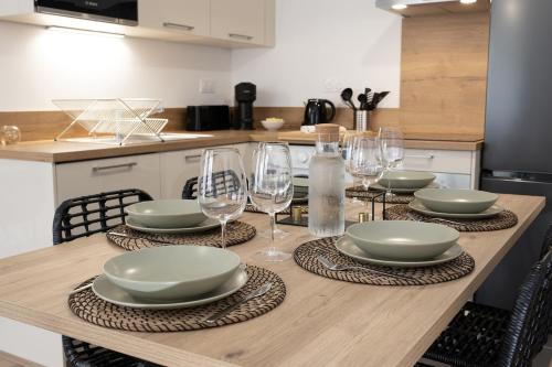 une table avec des assiettes et des verres à vin dessus dans l'établissement Le Normand - Spacieux T4 neuf avec 3 salles d’eaux, à Rennes