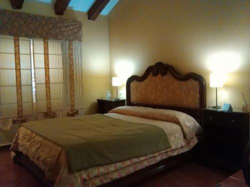 a bedroom with a bed and two lamps and two windows at Casa Rural Valdevilano in La Roca de la Sierra
