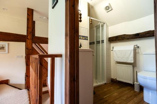 ein Badezimmer mit Toilette und Glasdusche in der Unterkunft The Threshing Barn - Stunning 5 Bedroom Retreat! in Sedgeberrow