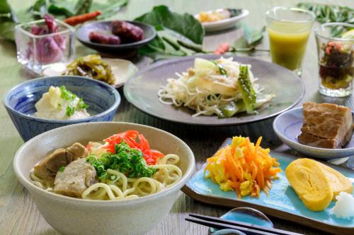ein Tisch mit Tellern mit Essen und Schüsseln mit Pasta in der Unterkunft Art Hotel Ishigakijima in Ishigaki-jima
