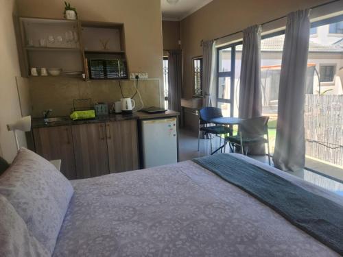 a bedroom with a bed and a kitchen with a table at Balmoral Cottage, West Beach in Cape Town