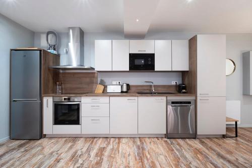 une cuisine avec des armoires blanches et des appareils en acier inoxydable dans l'établissement Les Ponts, à Nancy