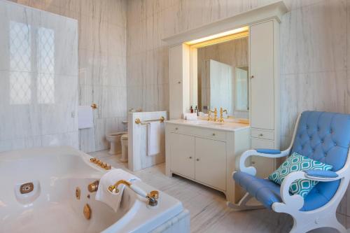 a white bathroom with a tub and a blue chair at Villa del Cavaliere Berico in Vicenza