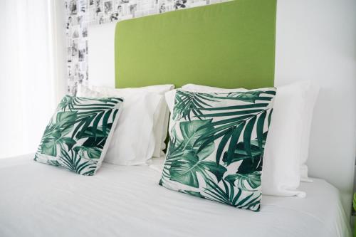 a bed with green and white pillows on it at By the Sea - Nazaré in Nazaré