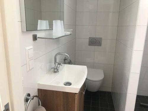 a white bathroom with a sink and a toilet at t Ateliertje Noort in Bergen