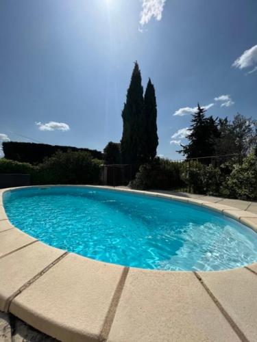 une piscine avec de l'eau bleue dans une cour dans l'établissement L'Isle en coeur air-conditioned house with garden and swimming pool, à LʼIsle-sur-la-Sorgue