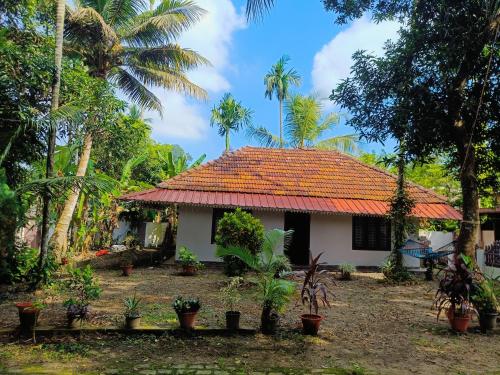 a house with an orange roof and some palm trees at Bougainvilla in Alleppey