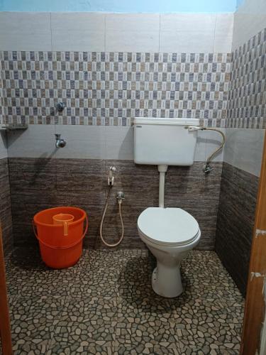 a bathroom with a toilet and a bucket at Bougainvilla Homestay in Alleppey