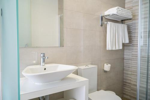 a bathroom with a sink and a toilet and a mirror at By the Sea - Nazaré in Nazaré
