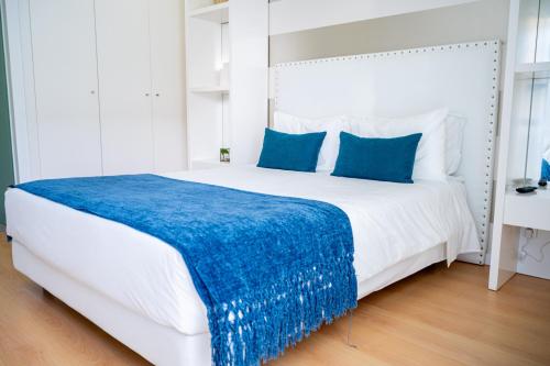 a bedroom with a large white bed with a blue blanket at By the Sea - Nazaré in Nazaré