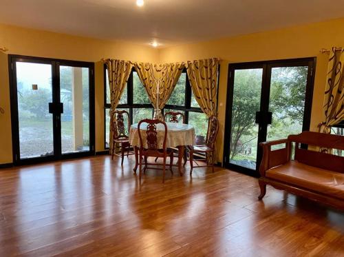 a dining room with a table and chairs and large windows at CitrusHill Family Glamping dan Villa Syariah Kebun Lemon in Ciater