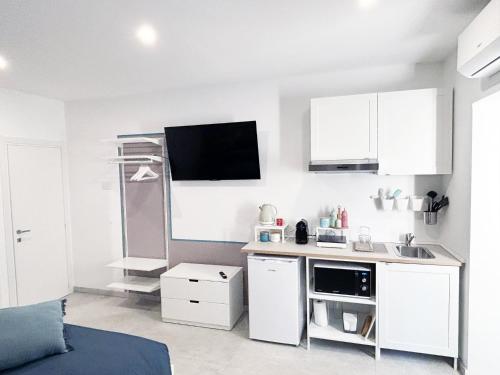 a kitchen with white cabinets and a tv on the wall at La Bouganville in Assisi
