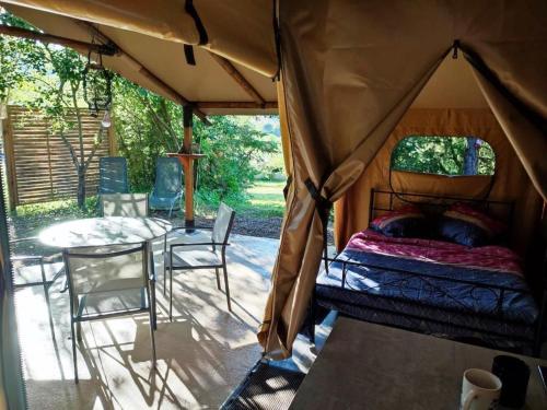 une tente avec un lit, une table et des chaises dans l'établissement Camping des vignes, à Dun