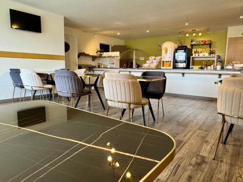 a restaurant with chairs and a table and a counter at Kyriad Toulouse Sud - Roques in Roques Sur Garonne