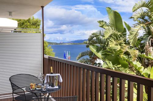 a balcony with a table and chairs and a view of the water at El Faro Hotel & Spa in Porto Conte