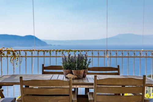 a wooden table with chairs and a basket of flowers at Aigaio pool Villa, gaze the sunset over the Aegean sea in Glóssa