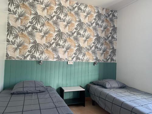 two beds in a room with a wallpaper with palm trees at gîtes "Entre les Vignes" in Tourreilles