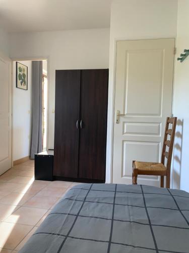 a bedroom with a wooden cabinet and a chair at gîtes "Entre les Vignes" in Tourreilles