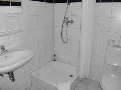 ein weißes Bad mit einer Dusche und einem Waschbecken in der Unterkunft Central-Hotel Eberswalde in Eberswalde-Finow