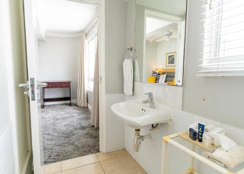 a white bathroom with a sink and a mirror at Peninsula All Suite Hotel by Dream Resorts in Cape Town