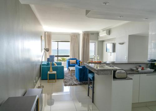 a kitchen with blue chairs and a living room at Peninsula All Suite Hotel by Dream Resorts in Cape Town